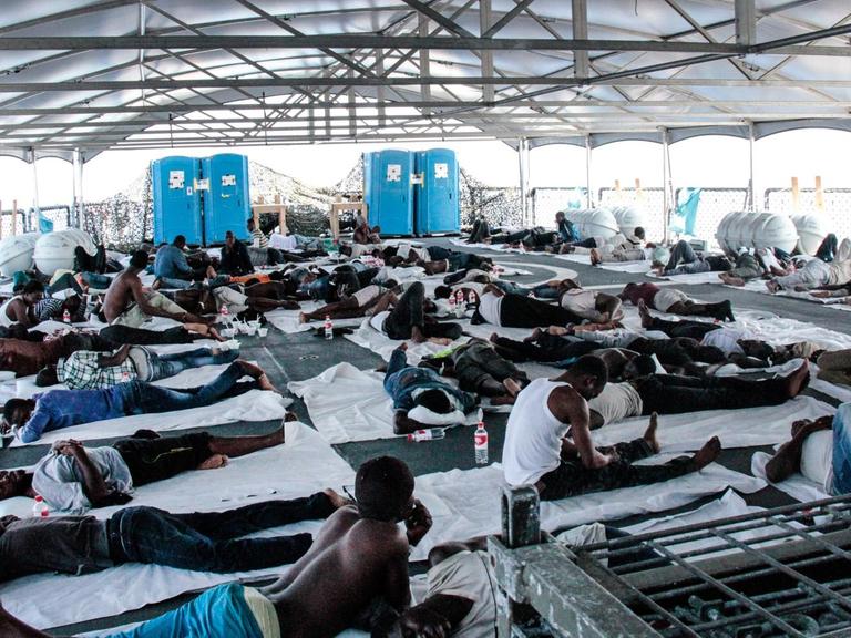 Schiffbrüchige auf dem Flugdeck des Tenders Werra. Am 15.08.2015 wurden 103 Menschen darunter 4 Frauen und 2 Kinder aus einem Schlauchboot gerettet.