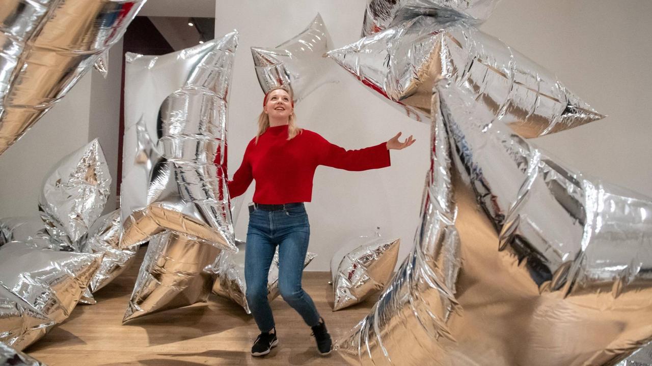 Eine Mitarbeiterin der Tate Modern Gallery spielt mit der Installation "Silver Clouds" in der Andy-Warhol-Ausstellung.