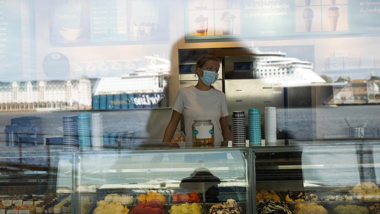 Eine Eisverkäuferin mit Mund-Nasen-Schutz in Oslo wartet auf Kundschaft, Norwegen, 25. April 2021. Eine Eisverkäuferin mit Mund-Nasen-Schutz in Oslo wartet auf Kundschaft, Norwegen, 25. April 2021.