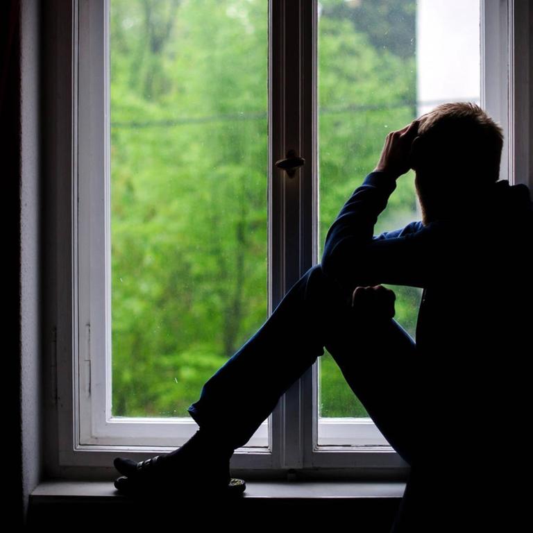 Ein Mann sitzt an einem Fenster und schaut raus