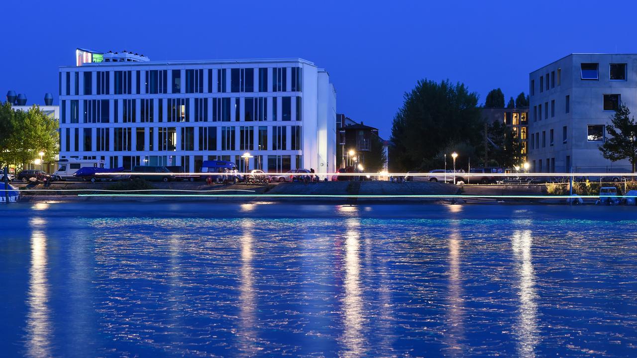 Die Fenster der Hochschule Konstanz für Technik, Wirtschaft und Gestaltung (HTWG) sind am 12.07.2017 in Konstanz nach Sonnenuntergang teils hell beleuchtet. Zu sehen ist das L-Gebäude (r) der HTWG. Im Vordergrund fließt der Seerhein.