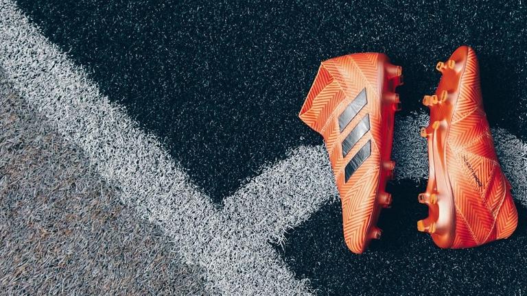 Ein paar Sportschuhe in orange liegt auf einem garuen Kunstrasen. Ein paar Sportschuhe in orange liegt auf einem garuen Kunstrasen.