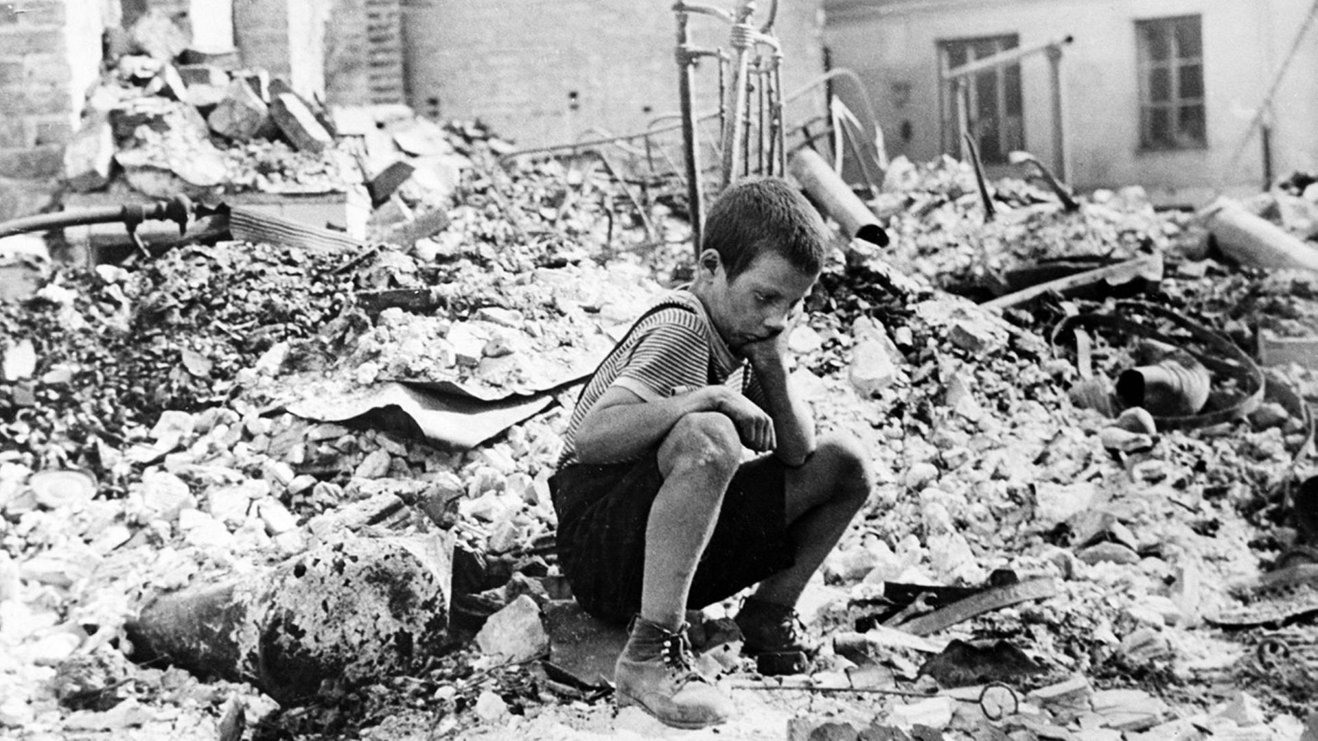 Junge sitzt in Warschau auf einem Trümmerhaufen