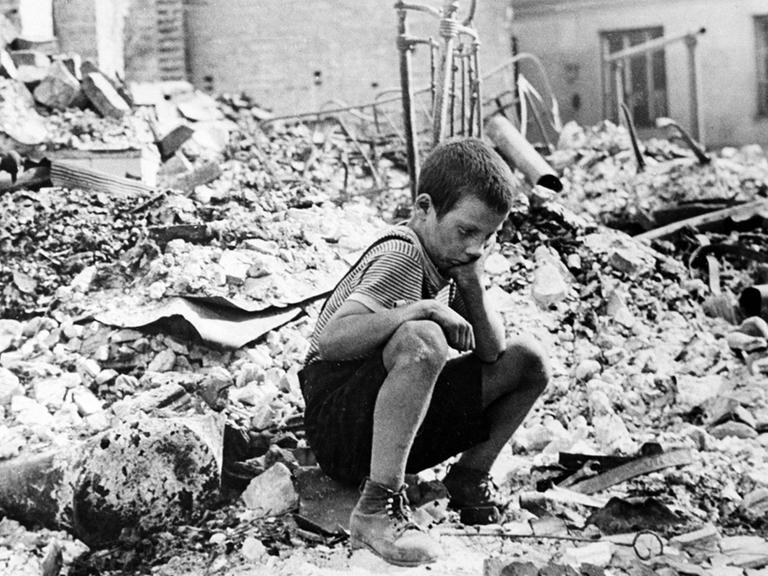 Junge sitzt in Warschau auf einem Trümmerhaufen