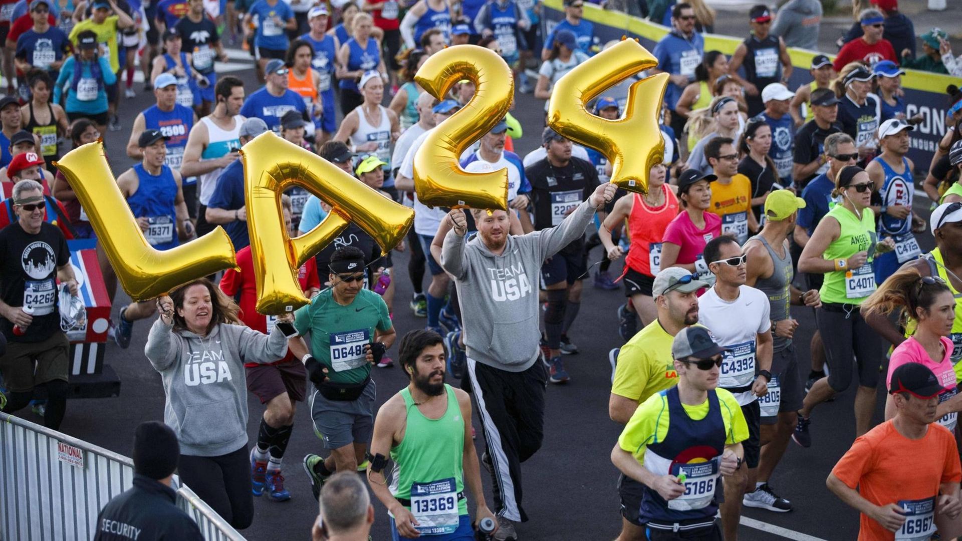 Läufer beim LA-Marathon werben für die Olympische Spiele 2024 in ihrer Stadt. Läufer beim LA-Marathon werben für die Olympische Spiele 2024 in ihrer Stadt.