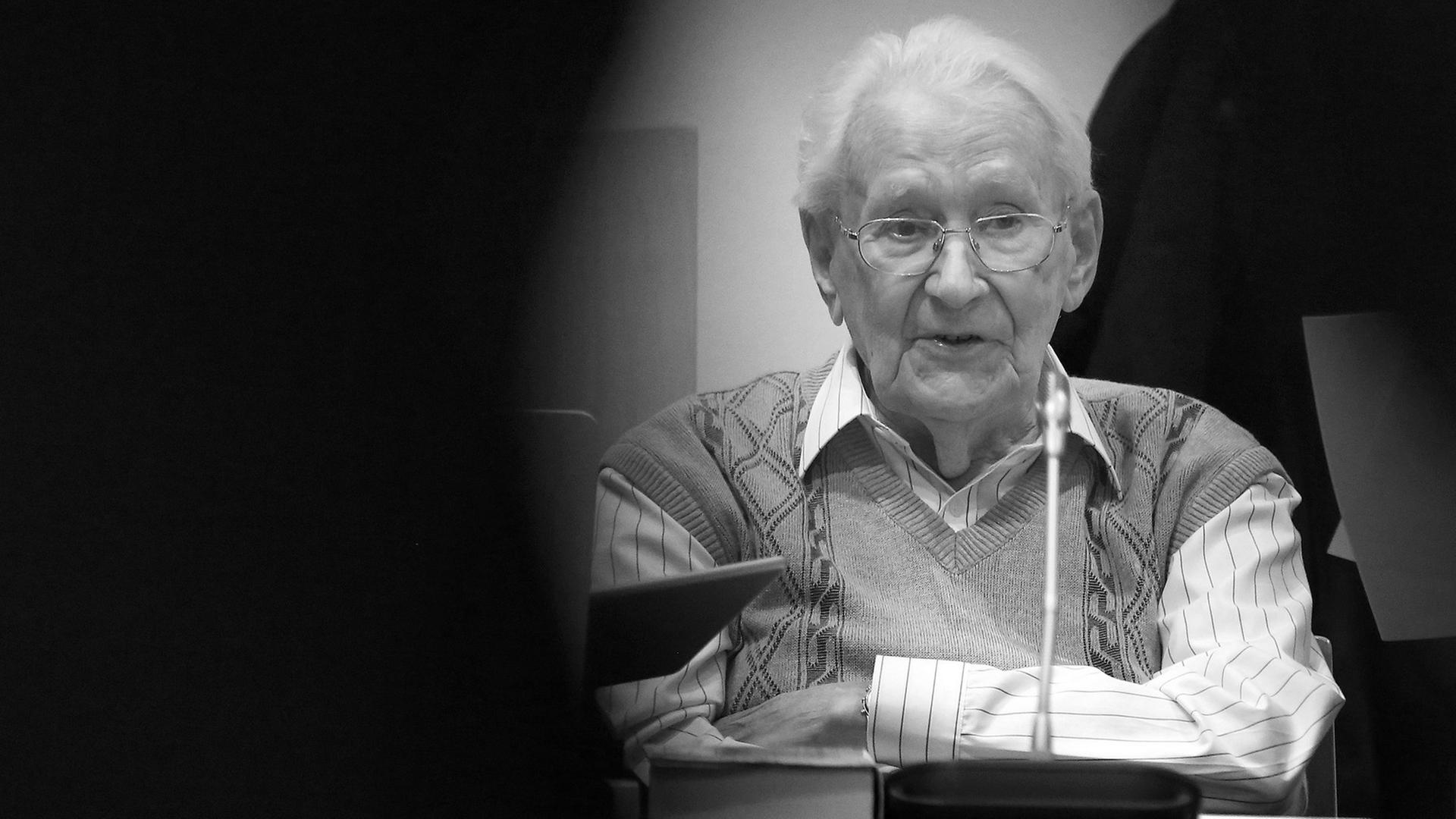 Oskar Gröning sitzt mit verschränkten Armen auf der Anklagebank. Oskar Gröning sitzt mit verschränkten Armen auf der Anklagebank.