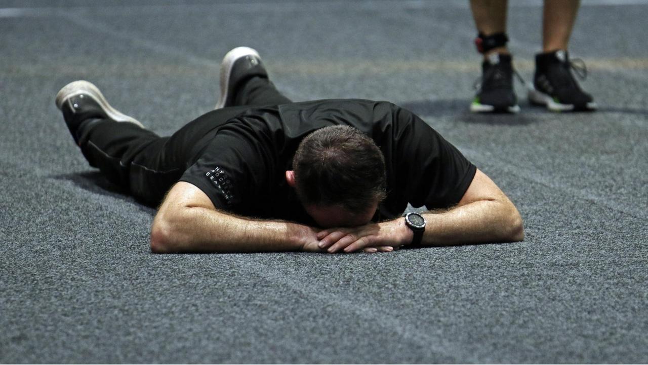 Ein Teilnehmer liegt erschöpft am Boden des Fitness-Wettbewerbs Hyrox 2019 in Hamburg. 