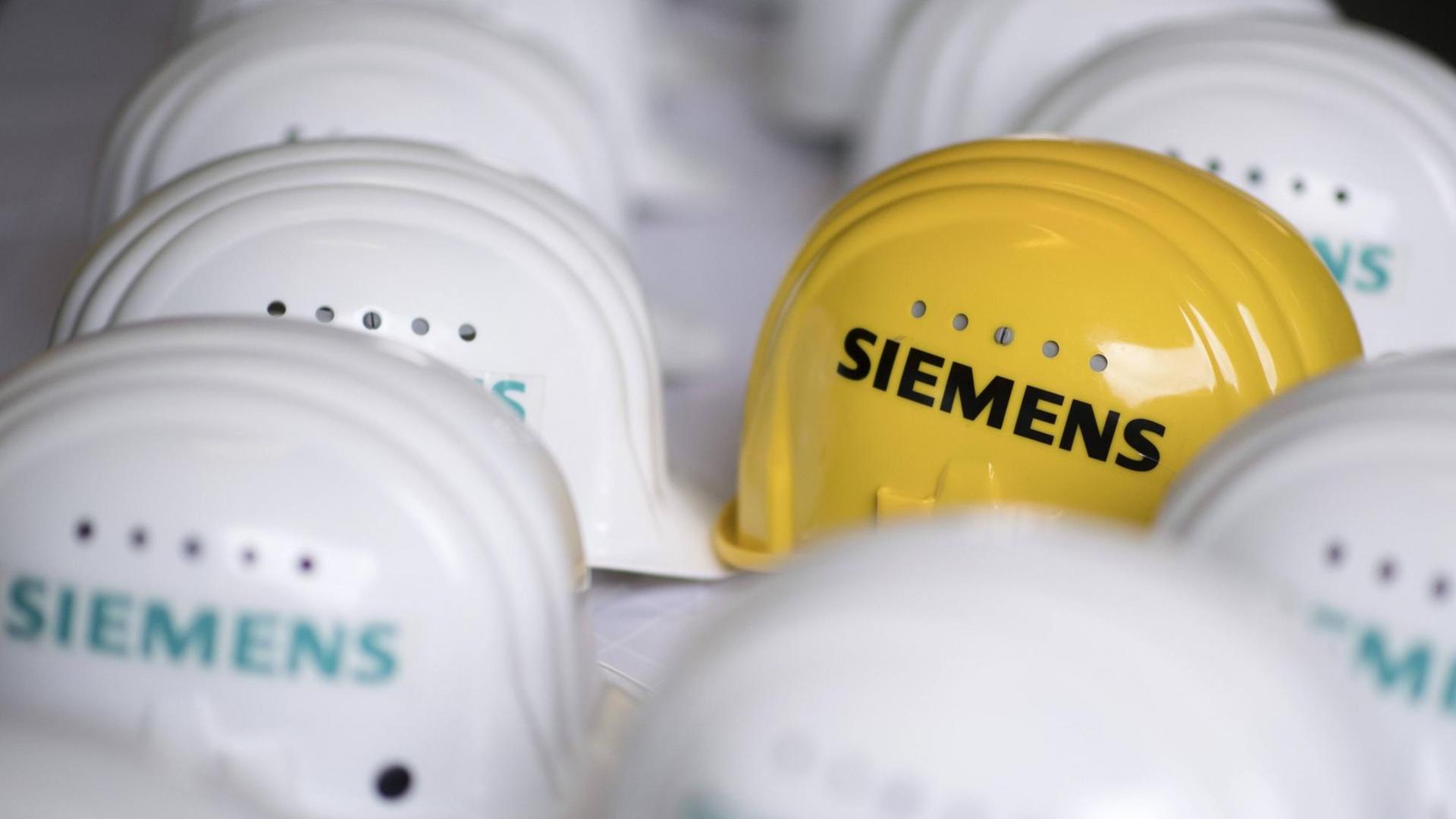 Logo der Siemens AG auf einem gelben Schutzhelm im Siemens-Gasturbinenwerk bei der Siemens AG in der Turbinenhalle in Berlin. Logo der Siemens AG auf einem gelben Schutzhelm im Siemens-Gasturbinenwerk bei der Siemens AG in der Turbinenhalle in Berlin.
