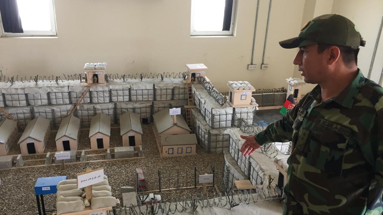 Ein Oberst der afghanischen Streitkräfte zeigt auf ein Sandkastenmodell. Ein Oberst der afghanischen Streitkräfte zeigt auf ein Sandkastenmodell.