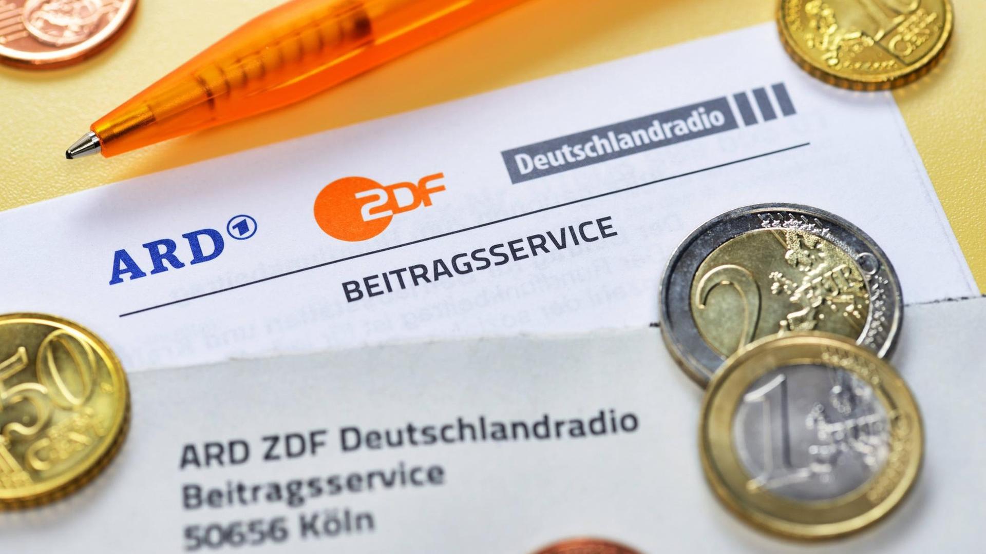Das Bild zeigt ein Schreiben des Beitragsservices von ARD, ZDF und Deutschlandradio mit den drei Senderlogos. Zu sehen sind zudem Geldmünzen und ein Stift. Das Bild zeigt ein Schreiben des Beitragsservices von ARD, ZDF und Deutschlandradio mit den drei Senderlogos. Zu sehen sind zudem Geldmünzen und ein Stift.
