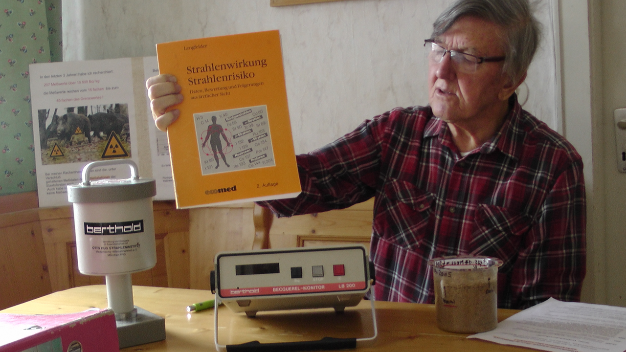 Helmut Rummel sitzt an seinem Küchentisch. In der Hand hält er ein Buch über Strahlenrisiken. Auf dem Tisch steht ein Geigerzähler. Helmut Rummel sitzt an seinem Küchentisch. In der Hand hält er ein Buch über Strahlenrisiken. Auf dem Tisch steht ein Geigerzähler.