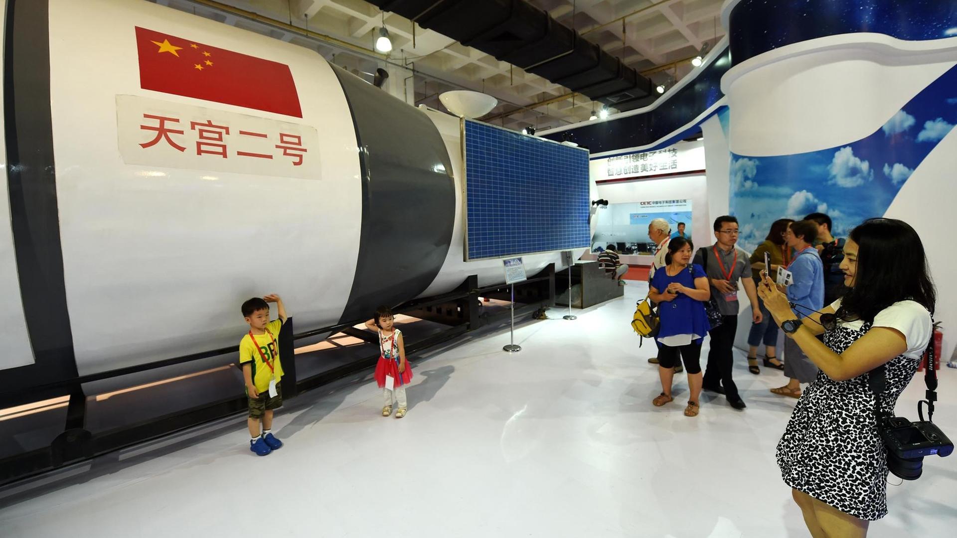 Besucher stehen in Peking auf der Internationalen Hightech-Ausstellung vor einem Modell des chinesischen Raumlabors Tiangong-2. Besucher stehen in Peking auf der Internationalen Hightech-Ausstellung vor einem Modell des chinesischen Raumlabors Tiangong-2.