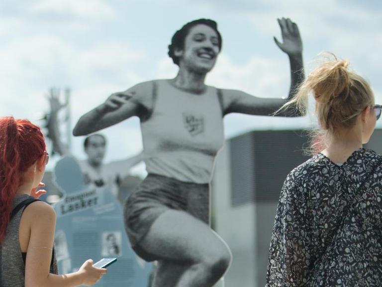 Zwei Frauen betrachten die Skulptur der Leichtathletin Gretel Bergmann.
