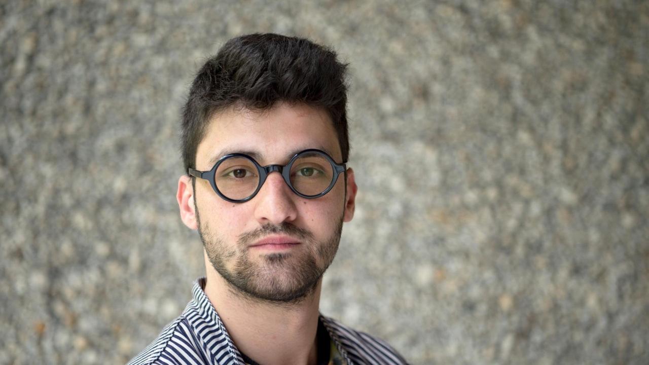 Der Regisseur Ersan Mondtag, aufgenommen vor einer grauen Steinwand Der Regisseur Ersan Mondtag, aufgenommen vor einer grauen Steinwand