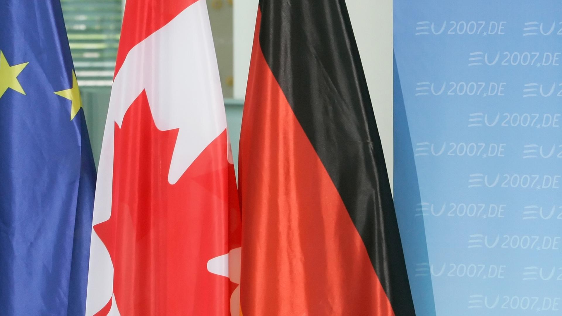 Die Fahnen der Europäischen Union (EU), Kanadas (M) und der Bundesrepublik Deutschland (r) stehen am Montag (04.06.2007) im Kanzleramt in Berlin vor einer Pressekonferenz neben einer Stellwand, auf der der Schriftzug "EU2007.DE" zu lesen ist. Die Fahnen der Europäischen Union (EU), Kanadas (M) und der Bundesrepublik Deutschland (r) stehen am Montag (04.06.2007) im Kanzleramt in Berlin vor einer Pressekonferenz neben einer Stellwand, auf der der Schriftzug "EU2007.DE" zu lesen ist.