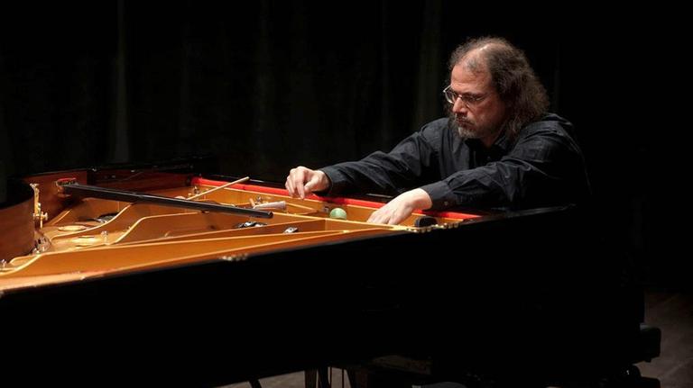 Der Pianist und Komponist Steffen Schleiermacher an einem Flügel, seine Hände bespielen Saiten im Inneren des Inlstrumentes