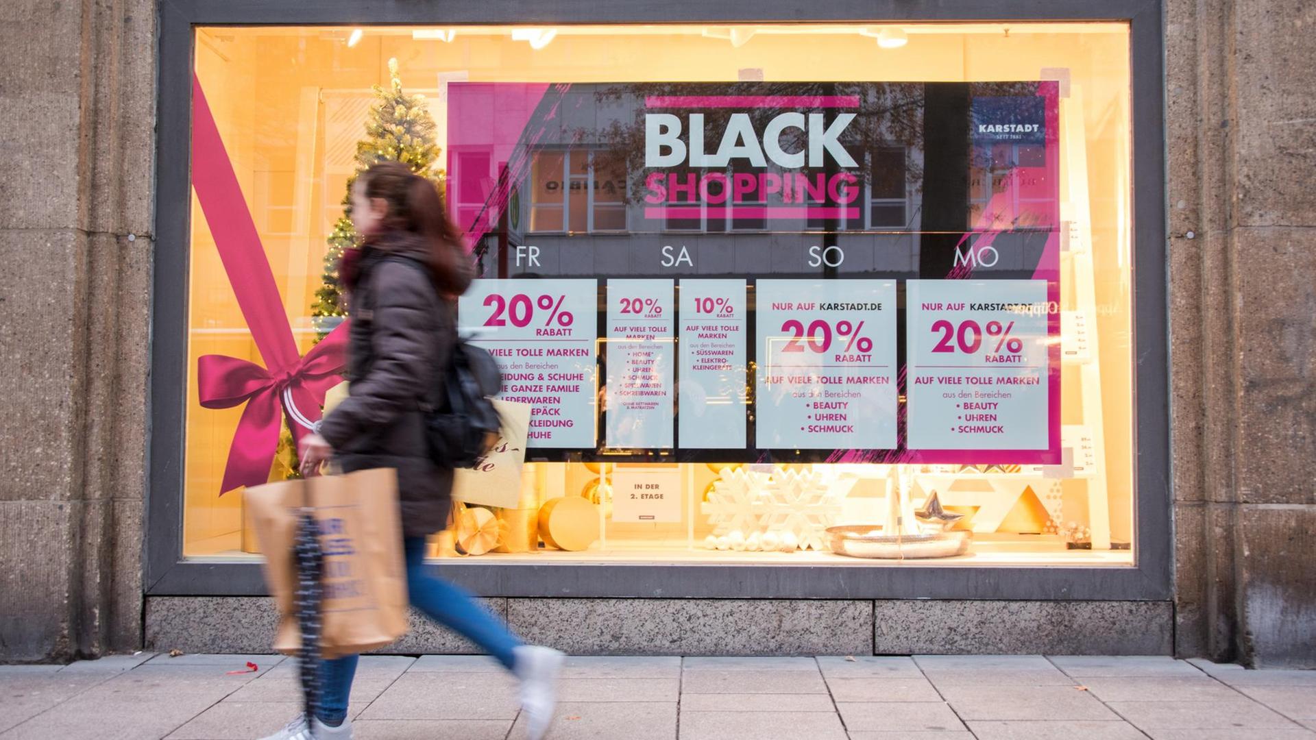 Eine shoppende Frau geht am 24.11.2017, dem Black Friday, in Hamburg am Schaufenster eines Geschäfts entlang. Eine shoppende Frau geht am 24.11.2017, dem Black Friday, in Hamburg am Schaufenster eines Geschäfts entlang.