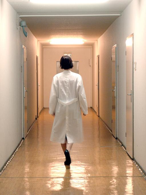 Eine Ärztin läuf allein einen Flur einer Krankenstation in einem Berliner Krankenhaus entlang.