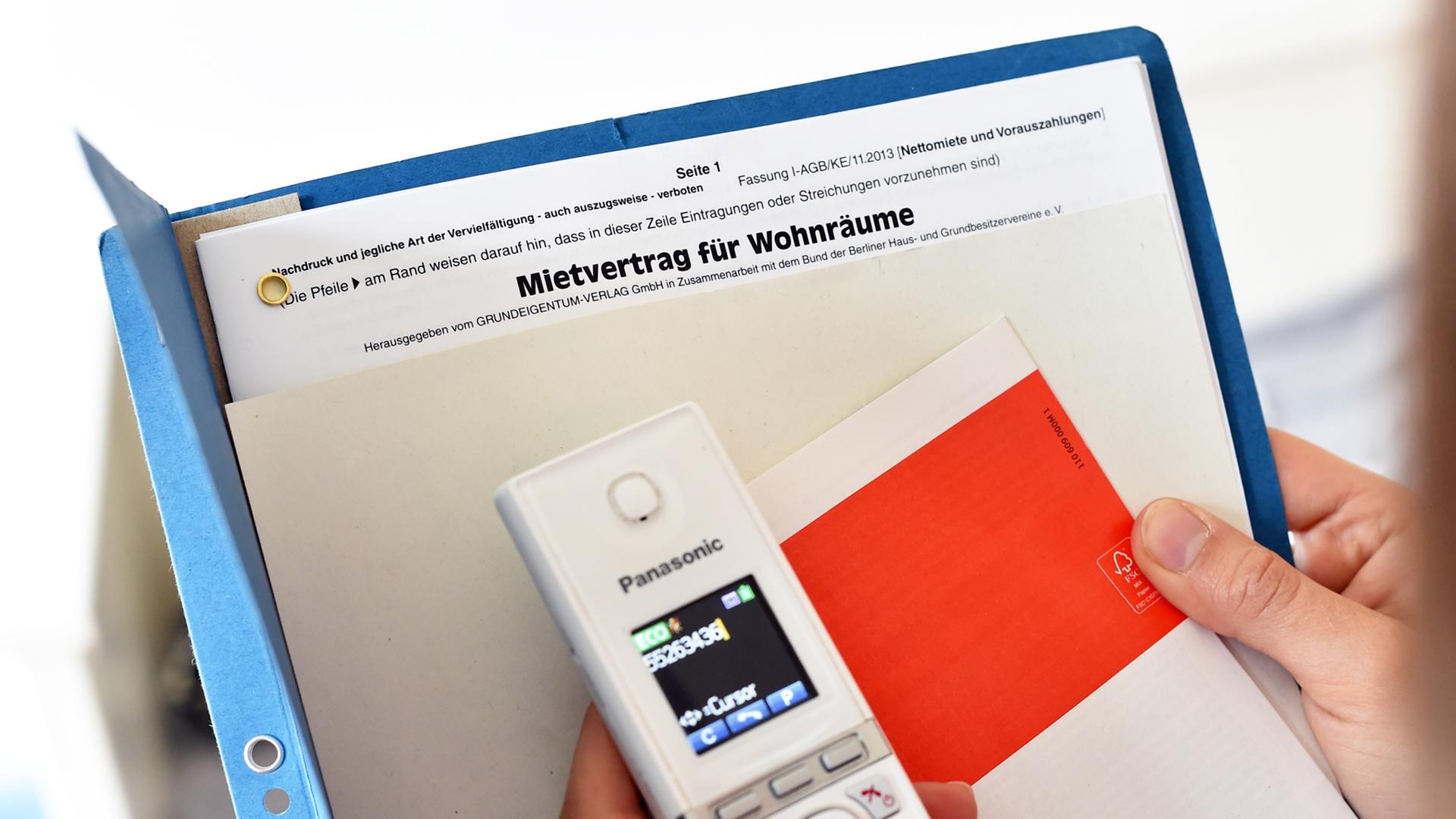Eine Frau hält ein Telefon und einen Mietvertrag in den Händen. Eine Frau hält ein Telefon und einen Mietvertrag in den Händen.