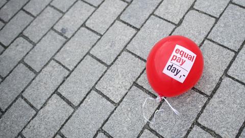 Ein Ballon mit "Equal Pay Day" liegt auf der Straße.