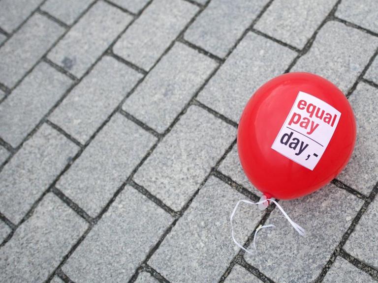Ein Ballon mit "Equal Pay Day" liegt auf der Straße.