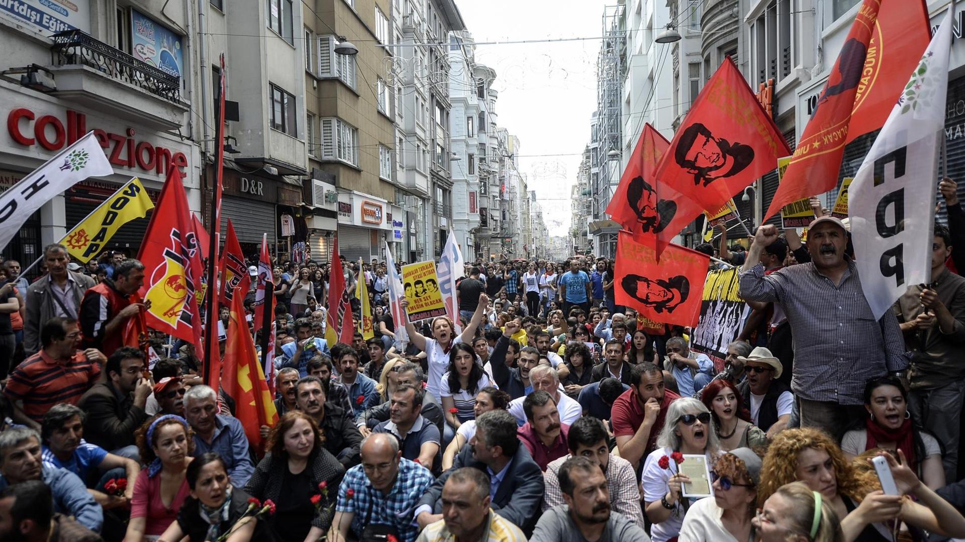 Eine Menschenmenge sitzt und steht auf einer engen Einkaufsstraße in Istanbul.