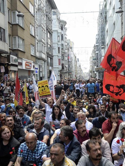Eine Menschenmenge sitzt und steht auf einer engen Einkaufsstraße in Istanbul.
