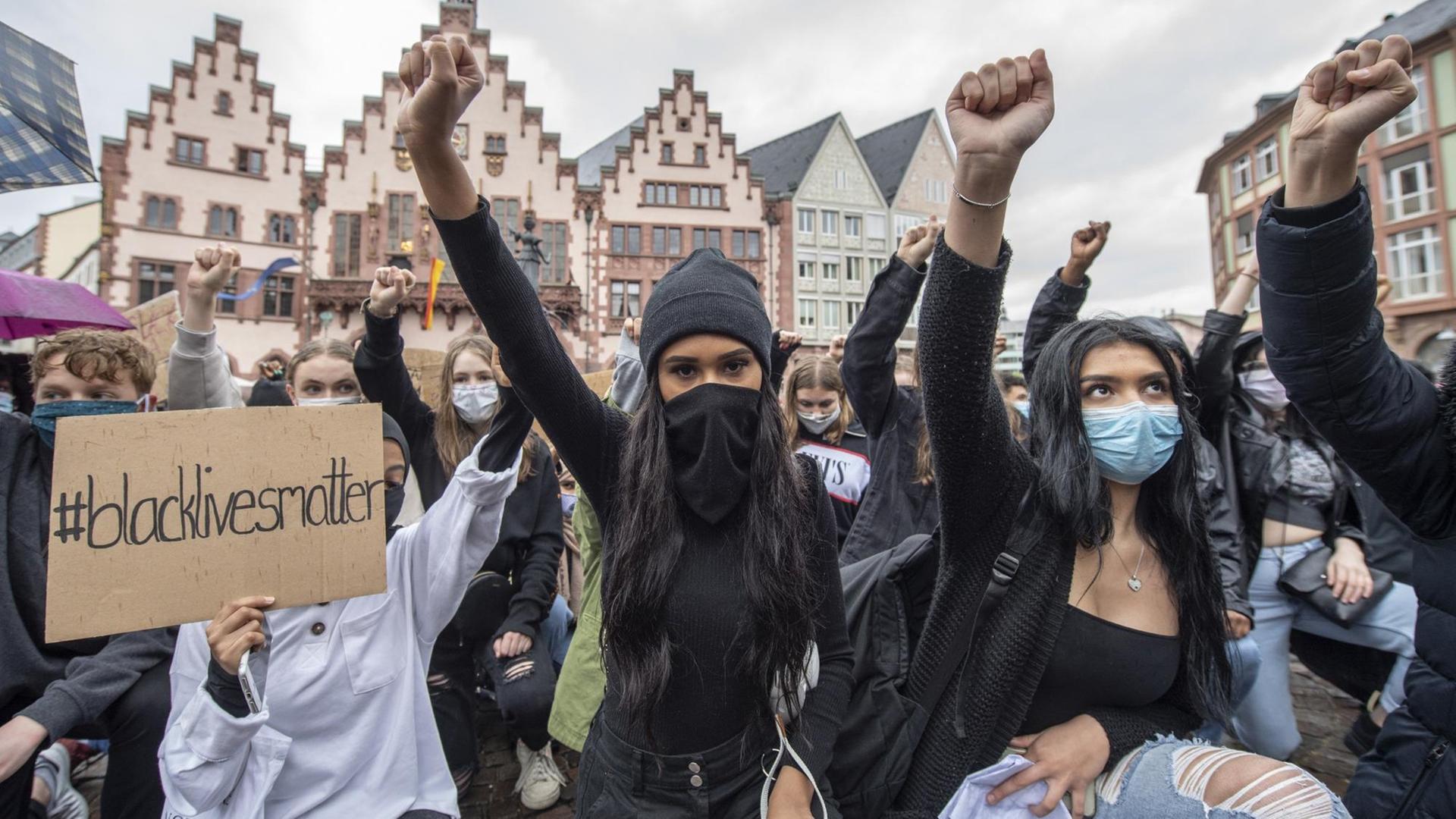 Auf Knien und mit in die Höhe gestreckter Faust bekunden Demonstrantinnen auf dem Römerberg in Frankfurt ihre Solidarität mit den Anti-Rassismus-Protesten in den USA.