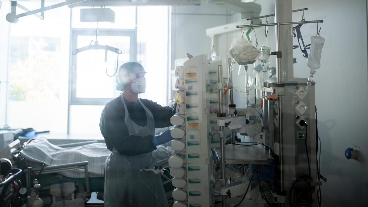 Eine Mitarbeiterin der Pflege steht in einem Patientenzimmer auf der Corona-Intensivstation des Universitätsklinikums Essen Eine Mitarbeiterin der Pflege steht in einem Patientenzimmer auf der Corona-Intensivstation des Universitätsklinikums Essen