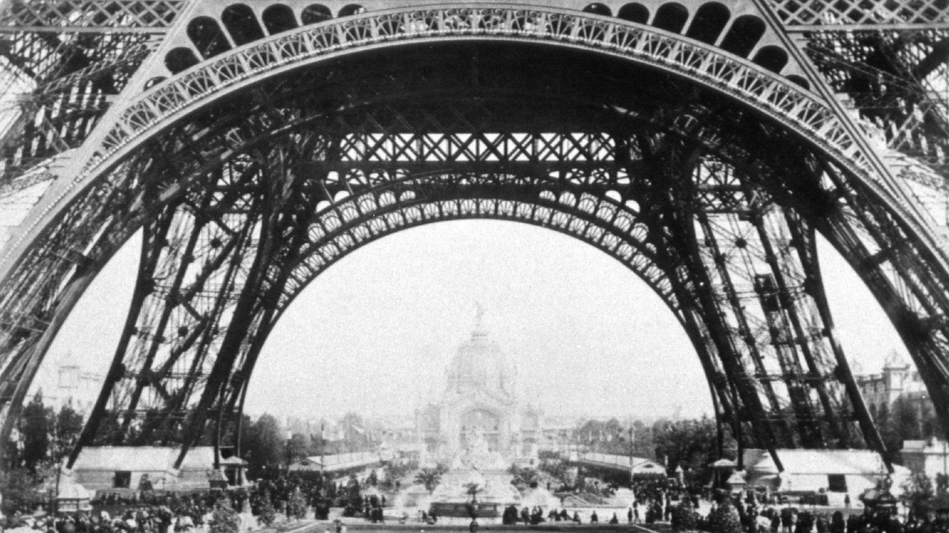 Ausstellungsbesucher der Weltausstellung in Paris 1889 wandeln unter dem Eiffelturm. Ausstellungsbesucher der Weltausstellung in Paris 1889 wandeln unter dem Eiffelturm.