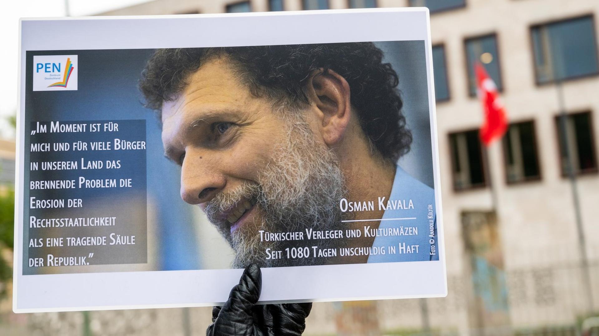 Ein Mann hält bei einer Mahnwache des PEN-Zentrums für den türkischen Verleger und Kulturmäzen Osman Kavala vor der Türkischen Botschaft ein Bild von Kavala.