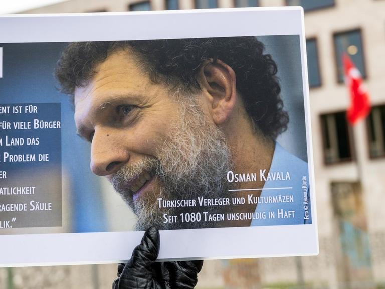 Ein Mann hält bei einer Mahnwache des PEN-Zentrums für den türkischen Verleger und Kulturmäzen Osman Kavala vor der Türkischen Botschaft ein Bild von Kavala.