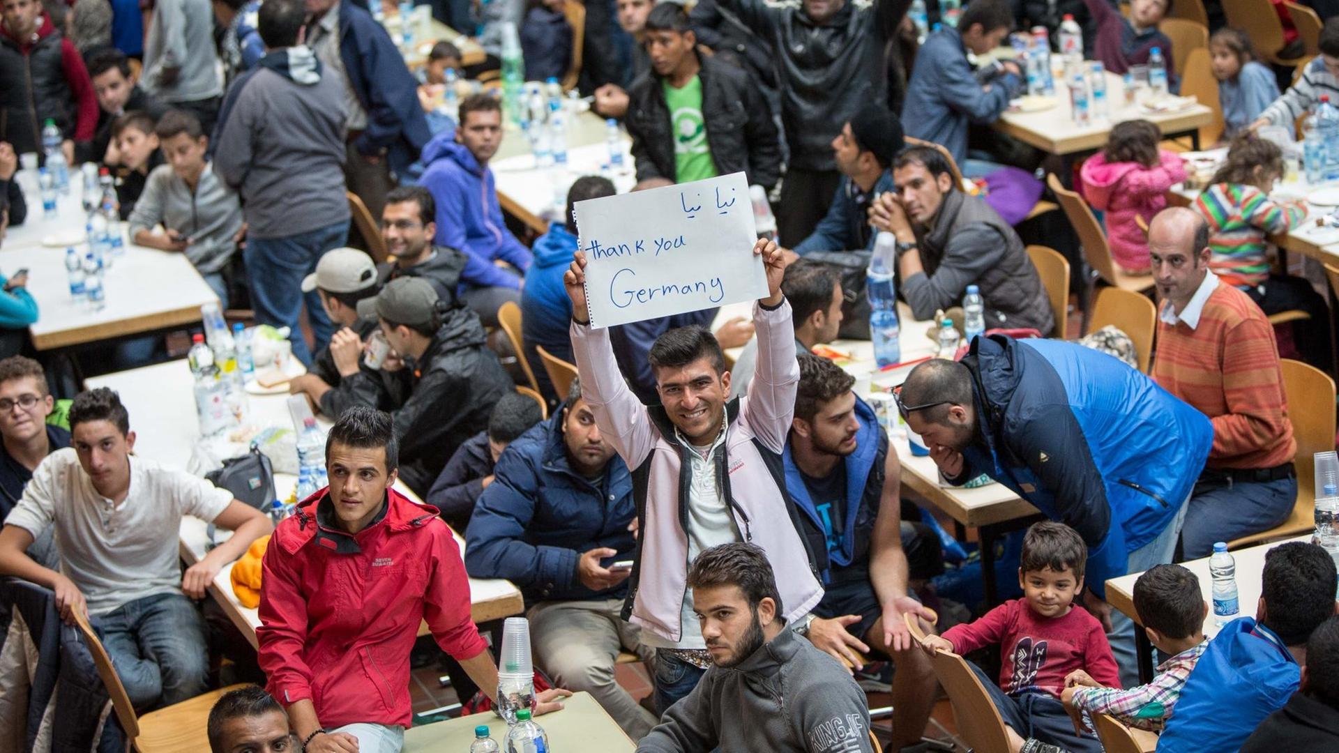 Flüchtlinge in Dortmund halten einen Zettel mit der Aufschrift "Thank you, Germany" hoch. Flüchtlinge in Dortmund halten einen Zettel mit der Aufschrift "Thank you, Germany" hoch.