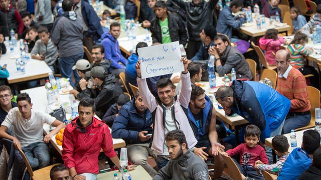 Flüchtlinge in Dortmund halten einen Zettel mit der Aufschrift "Thank you, Germany" hoch.