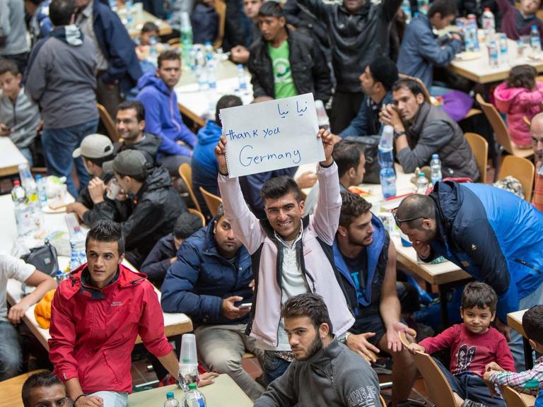 Flüchtlinge in Dortmund halten einen Zettel mit der Aufschrift "Thank you, Germany" hoch.