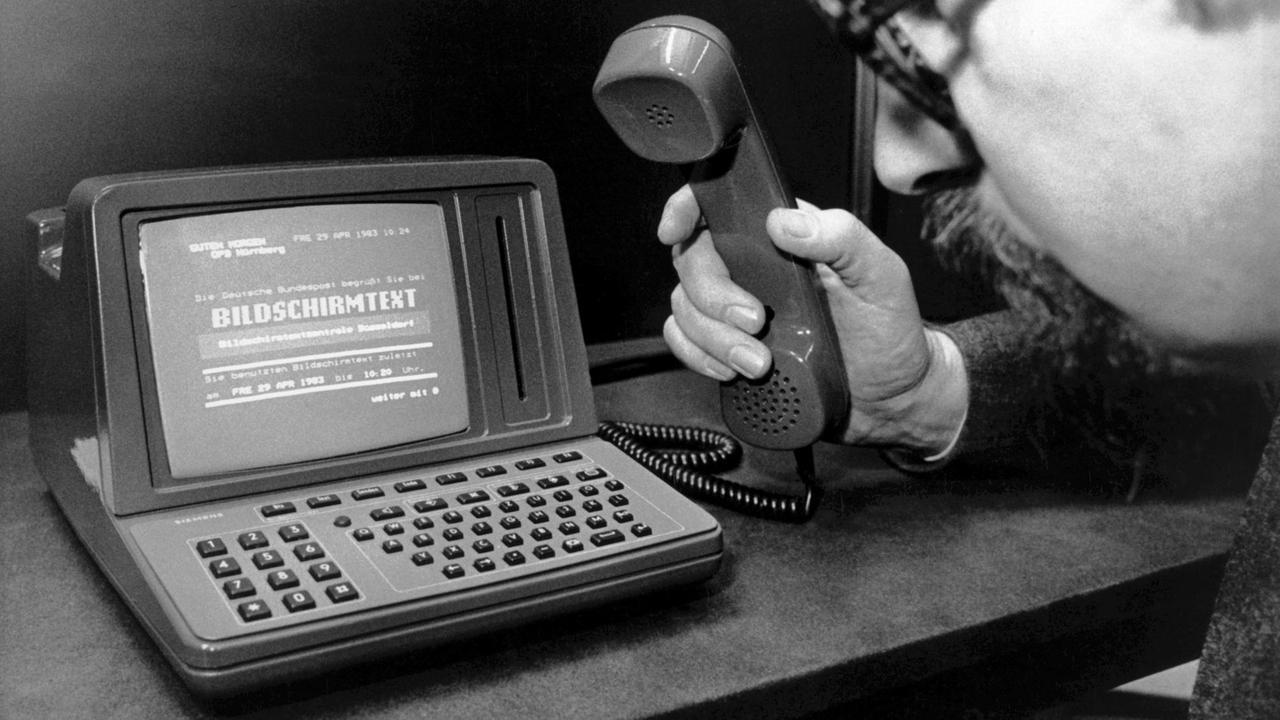 (Historisches Foto: Ein Mann hält einen Telefonhörer und blickt auf den Prototyp eines BTX-Terminals. Ausstellung  im Nürnberger Verkehrsmuseum "100 Jahre Telefon in Bayern" am 3. Mai 1983. 