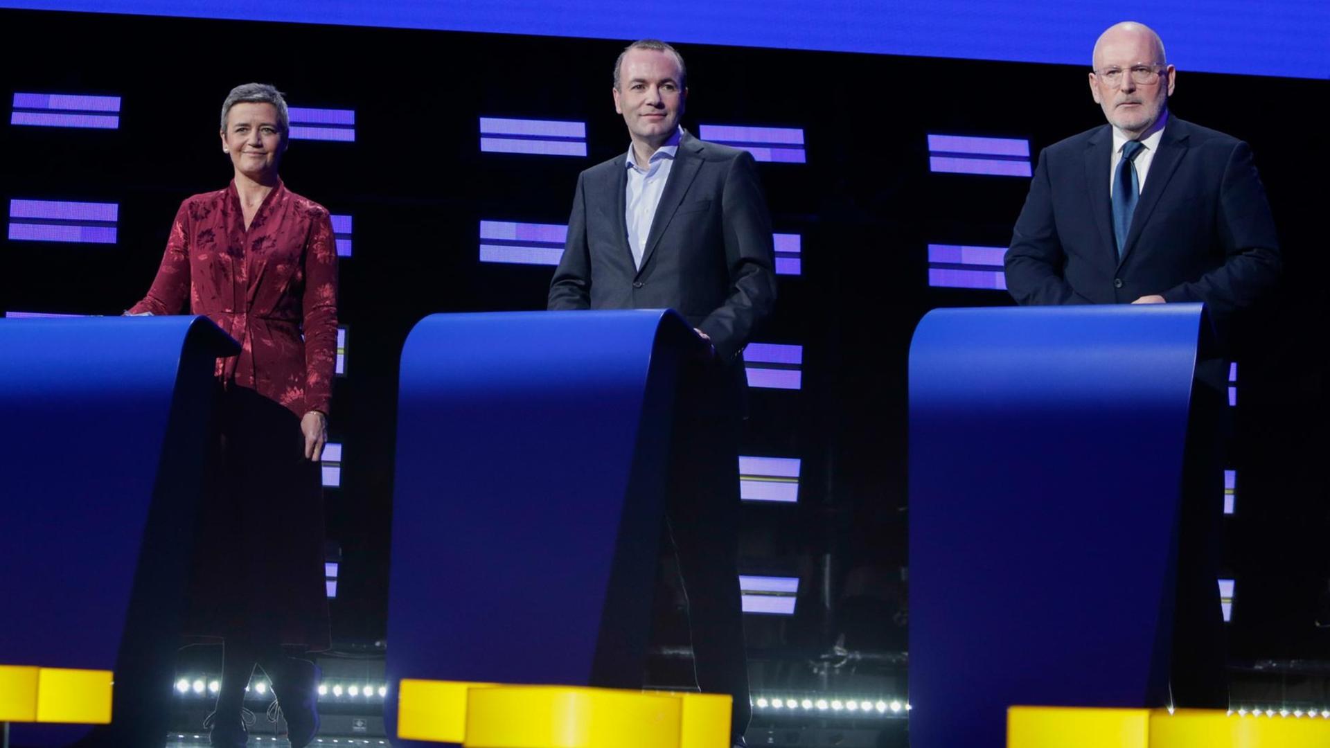 Margrethe Vestager, Manfred Weber und Frans Timmermans stehen nebeneinander jeweils hinter einem Pult auf einer Bühne Margrethe Vestager, Manfred Weber und Frans Timmermans stehen nebeneinander jeweils hinter einem Pult auf einer Bühne