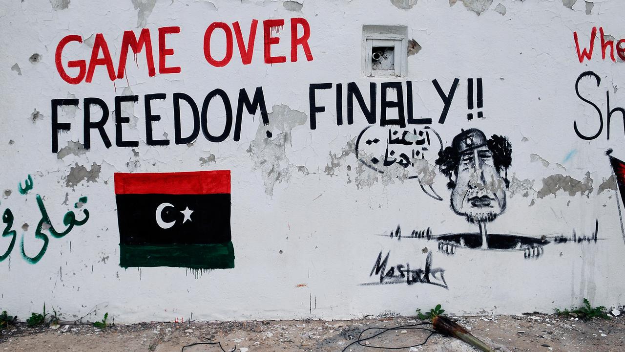     Bemalte Mauer in der libyschen Hauptstadt Tripolis: Zu sehen ist eine libysche Flagge in den Nationalfarben, die Aufschrift "Game over - Freedom finally" und ein Gaddafi, der aus einem Abfluss schaut und "hier bin ich, hier bin ich" ruft.