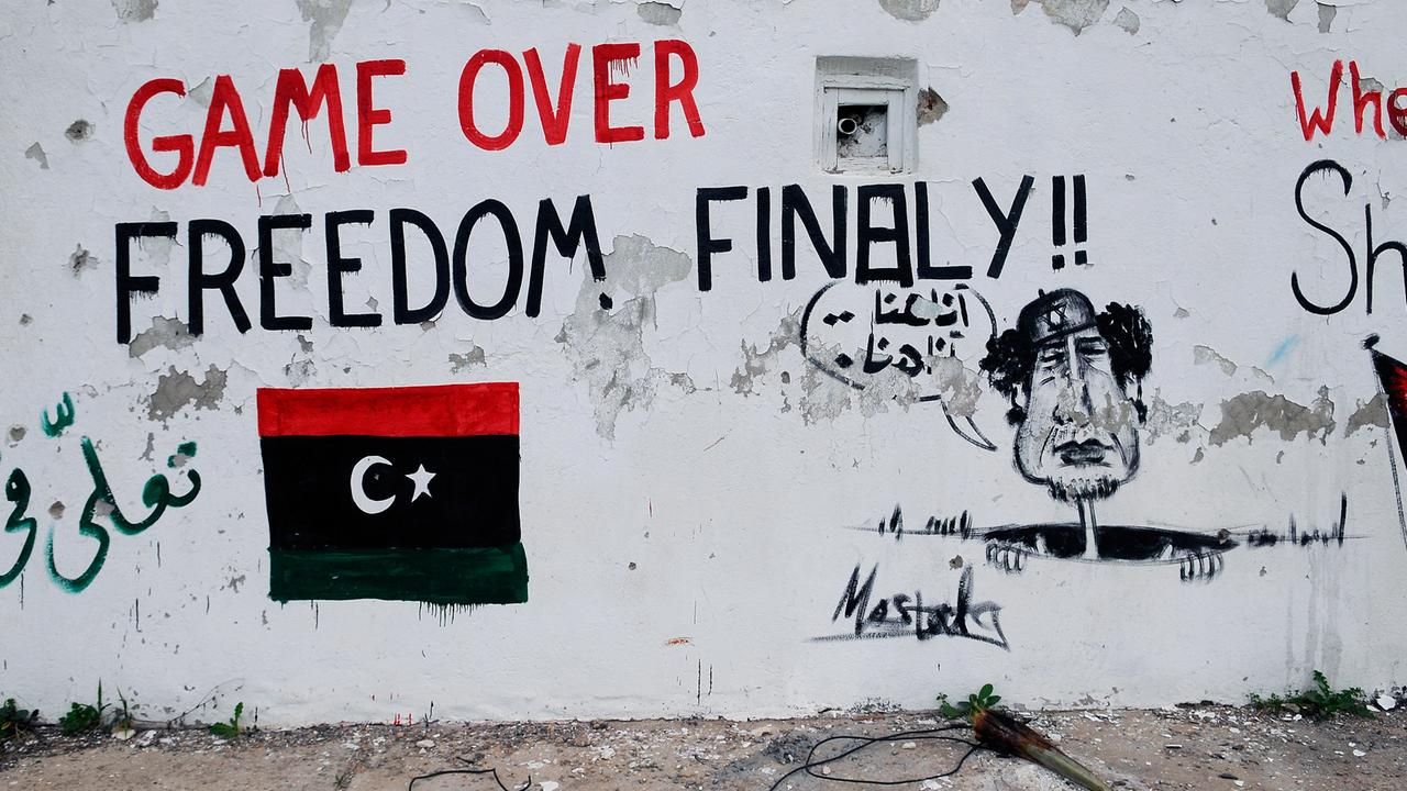 Bemalte Mauer in der libyschen Hauptstadt Tripolis: Zu sehen ist eine libysche Flagge in den Nationalfarben, die Aufschrift "Game over - Freedom finally" und ein Gaddafi, der aus einem Abfluss schaut und "hier bin ich, hier bin ich" ruft. Bemalte Mauer in der libyschen Hauptstadt Tripolis: Zu sehen ist eine libysche Flagge in den Nationalfarben, die Aufschrift "Game over - Freedom finally" und ein Gaddafi, der aus einem Abfluss schaut und "hier bin ich, hier bin ich" ruft.
