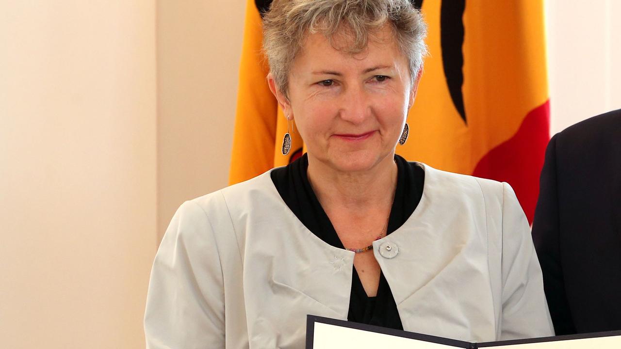 Gabriele Sötzer lächelnd vor einer Deutschlandfahne im Schloss Bellevue, sie hält eine Mappe mit der Urkunde zum Verdienstkreuz der Bundesrepublik vor sich. Gabriele Sötzer lächelnd vor einer Deutschlandfahne im Schloss Bellevue, sie hält eine Mappe mit der Urkunde zum Verdienstkreuz der Bundesrepublik vor sich.