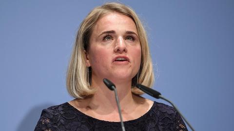 Porträt von Verena Bentele, Präsidentin des Sozialverbandes VdK. Sie trägt ein schwarzes Oberteil und spricht, hinter ihr eine blaugraue Wand.