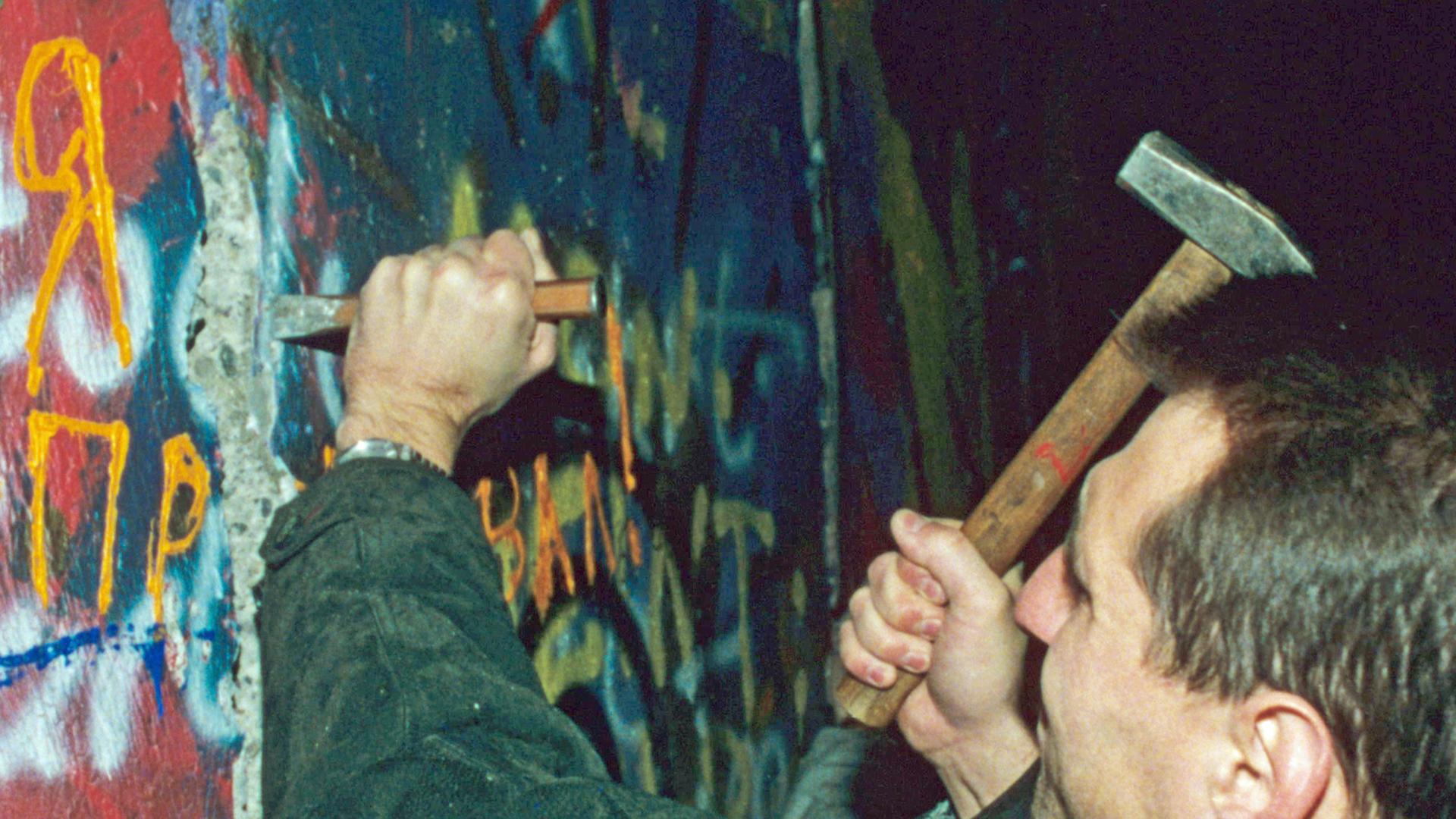 Ein Mauerspecht sichert sich einige Stücke (November 1989)