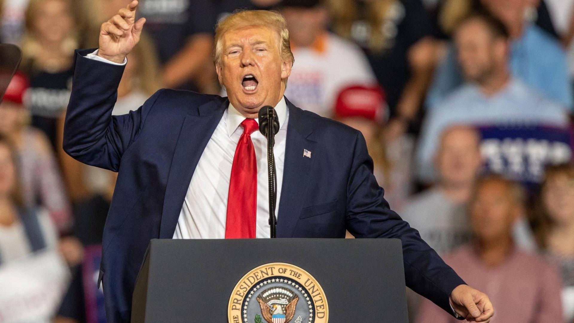 US-Präsident Trump steht an einem Rednerpult und gestikuliert mit der rechten Hand. Im Hintergrund sind Zuhörer zu sehen. US-Präsident Trump steht an einem Rednerpult und gestikuliert mit der rechten Hand. Im Hintergrund sind Zuhörer zu sehen.
