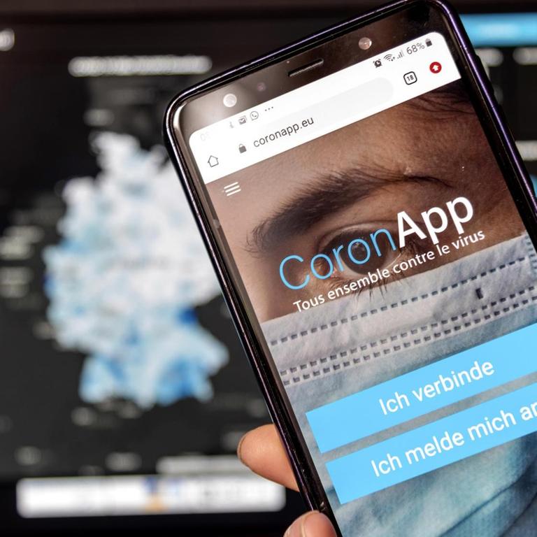 Die Freiwilige Corona-App "app.coronapp.eu" auf einem Handy-Display mit der Robert Koch Institut Website im Hintergrund.