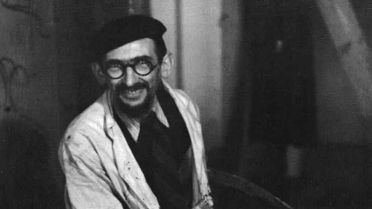 Schwarzweißfoto des Malers Horst Strempel, der in einem Kittel in seinem Atelier sitzt und freundlich in die Kamera blickt. Schwarzweißfoto des Malers Horst Strempel, der in einem Kittel in seinem Atelier sitzt und freundlich in die Kamera blickt.
