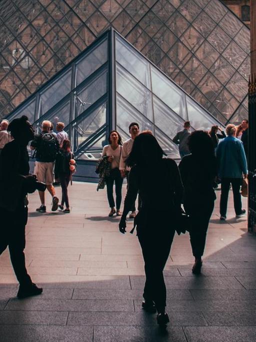 Blick durch einen Torbogen auf die Glaspyramide im Innenhof des Louvre.