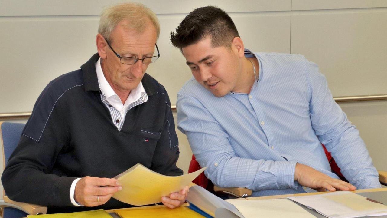 Bayern, Sonthofen: Ulrich Gampert (l), evangelischer Pfarrer, und ein afghanischer Flüchtling sitzen vor Verhandlungsbeginn auf ihrem Platz im Gerichtssal des Amtsgericht Sonthofen im Allgäu. 14 Monate lang hatte Gampert dem jungen Mann Kirchenasyl gewährt. Foto: Benjamin Liss/dpa | Verwendung weltweit Bayern, Sonthofen: Ulrich Gampert (l), evangelischer Pfarrer, und ein afghanischer Flüchtling sitzen vor Verhandlungsbeginn auf ihrem Platz im Gerichtssal des Amtsgericht Sonthofen im Allgäu. 14 Monate lang hatte Gampert dem jungen Mann Kirchenasyl gewährt. Foto: Benjamin Liss/dpa | Verwendung weltweit