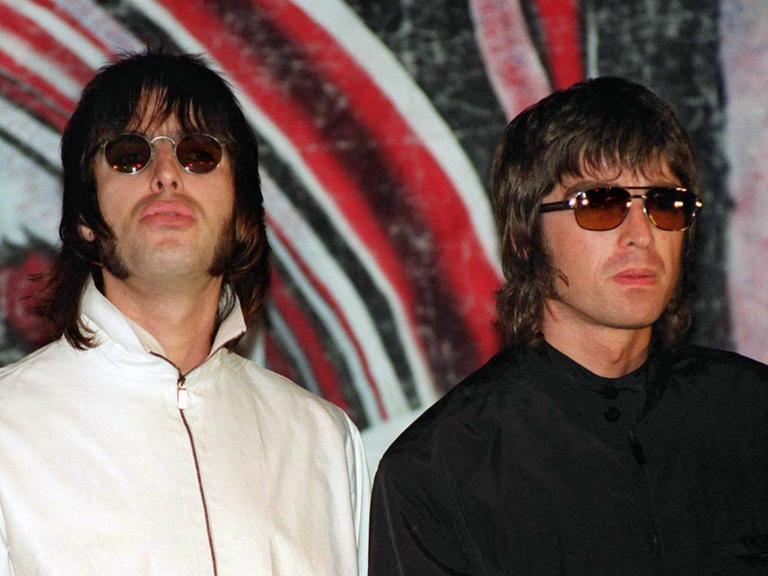 Liam (l.) und Noel Gallagher von der britischen Rockband Oasis bei einer Pressekonferenz 1999 in London, wo sie bekanntgaben, dass Bassist Paul "Guigsy" McGuigan angekündigt habe, die Band zu verlassen.