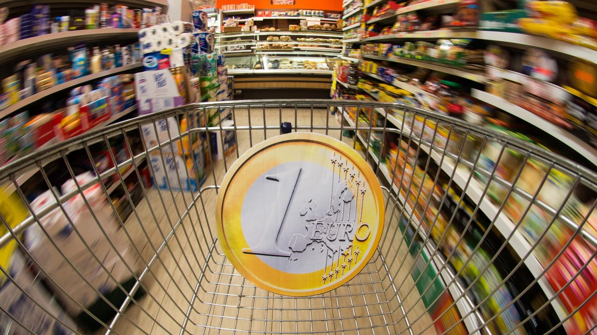 Eine überdimensionale Euromünze in einem Einkaufswagen Eine überdimensionale Euromünze in einem Einkaufswagen
