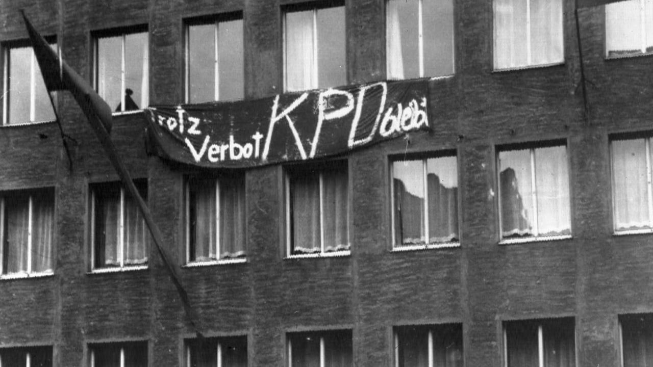 Das Haus der Bundesleitung der KPD am Morgen des 17.08.1956. Links weht eine rote Fahne aus einem Fenster, in der Mitte hängt ein Transparent mit der Aufschrift "Trotz Verbot KPD bleibt". Nachdem die Kommunistische Partei Deutschlands (KPD) am 17. August 1956 vom Karlsruher Verfassungsgericht verboten worden war, besetzten Kriminalbeamte und uniformierte Polizeieinheiten das Haus des Bundesvorstandes der KPD in Düsseldorf. Foto: Bernhard Frye +++(c) dpa - Report+++ | Verwendung weltweit Das Haus der Bundesleitung der KPD am Morgen des 17.08.1956. Links weht eine rote Fahne aus einem Fenster, in der Mitte hängt ein Transparent mit der Aufschrift "Trotz Verbot KPD bleibt". Nachdem die Kommunistische Partei Deutschlands (KPD) am 17. August 1956 vom Karlsruher Verfassungsgericht verboten worden war, besetzten Kriminalbeamte und uniformierte Polizeieinheiten das Haus des Bundesvorstandes der KPD in Düsseldorf. Foto: Bernhard Frye +++(c) dpa - Report+++ | Verwendung weltweit